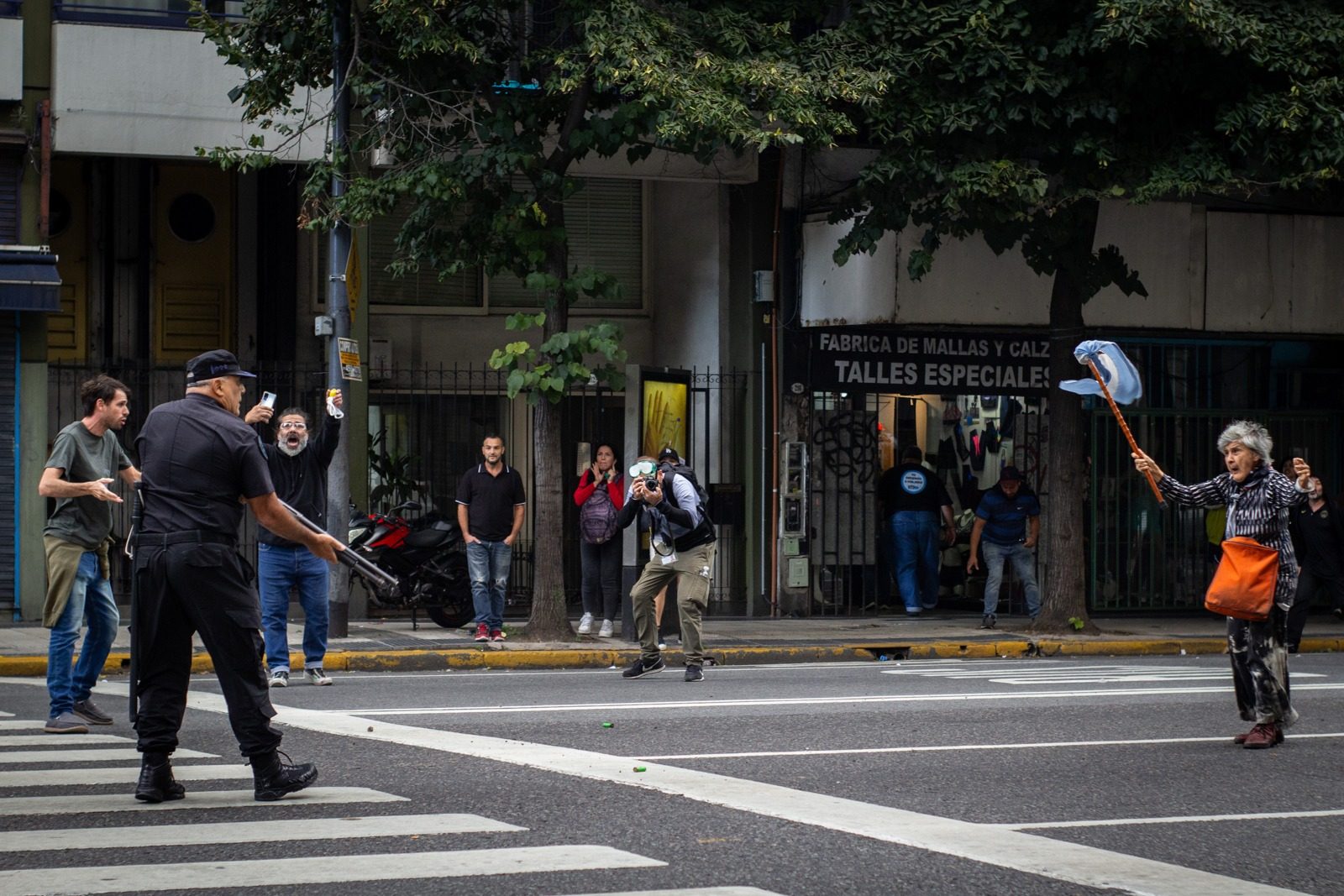 Un policía apunta con un arma larga a una mujer que avanza con un palo en alto durante la represión a la marcha de jubilados, en las inmediaciones del Congreso Nacional, en Buenos Aires, Argentina, el 12 de marzo de 2025.