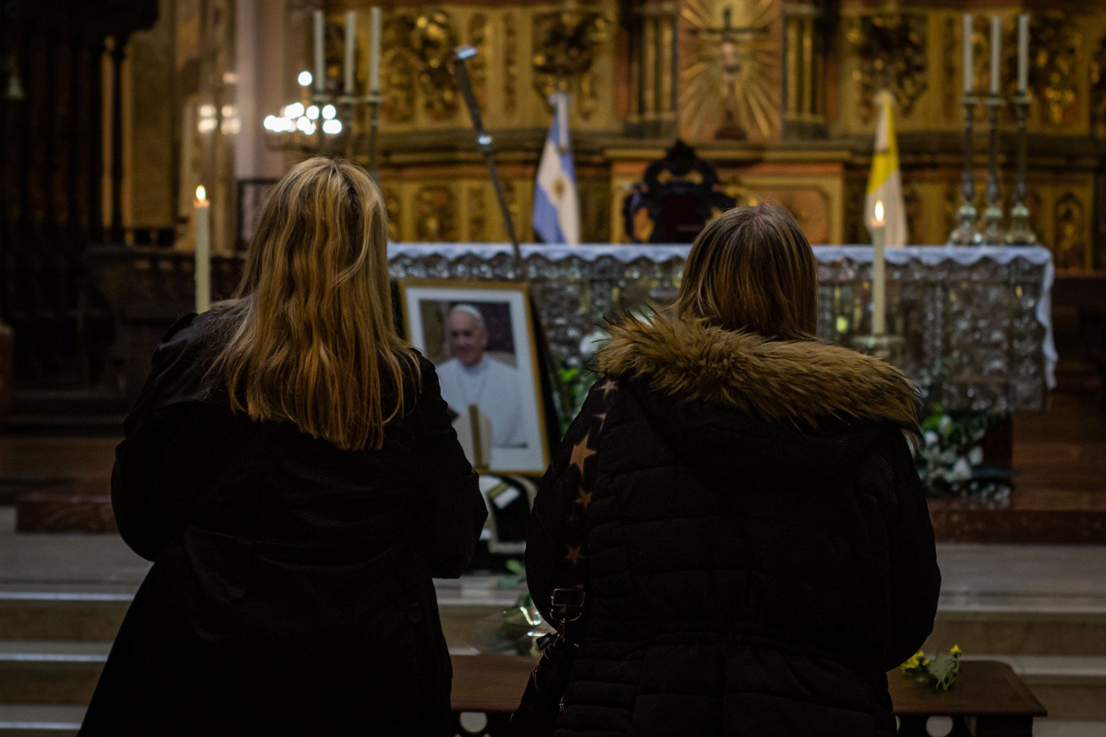 Two women look at a portrait of Pope Francis inside the Metropolitan Cathedral in Buenos Aires, Argentina, April 21, 2025.